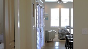 A hallway leading to a living area with a ceiling fan, a dining table, and a couch. - 404A The Hilltop House | 4BR/3.5BA | Balcony (Virginia Beach)