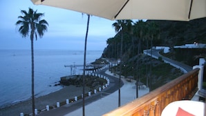 Ein Balkon mit Blick auf einen Strand, Palmen und eine gewundene Straße.
