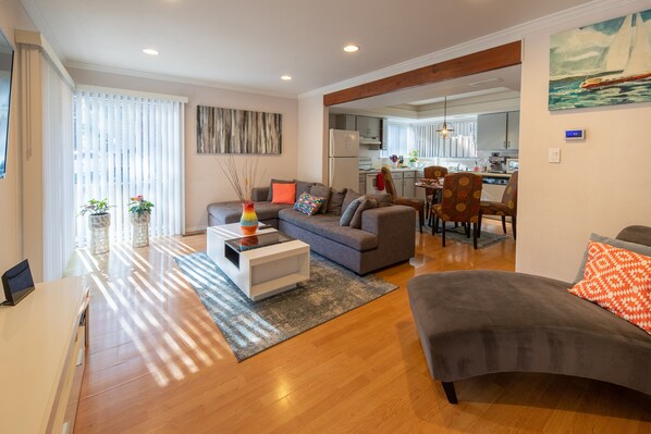A modern living room with a sofa, coffee table, and a dining area with chairs.