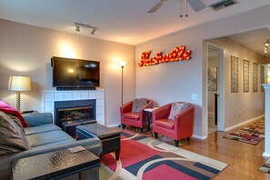 Relax in this stylish living room with a flat-screen TV above the fireplace, comfortable armchairs, and a cozy sofa.