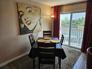 Enjoy meals with a view of the water from this dining area, featuring a table for four and a beautiful abstract art piece.