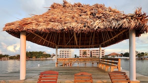 Une jetée en bois, dotée de bancs et surmontée d’une structure au toit de chaume.