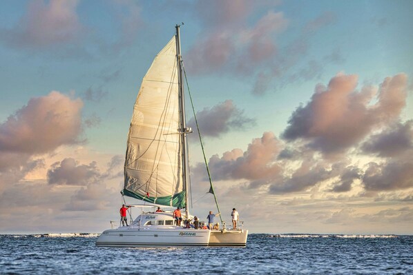 A sailboat with multiple people on deck, sailing on the water.
