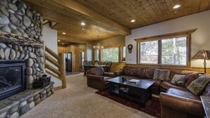 A spacious living room with a stone fireplace, wooden ceiling, and large windows. - Luxury Ski or Hiking retreat- 2 KING beds and more! (Park City)