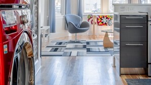 Una cocina moderna con un electrodoméstico rojo, una silla gris y una zona de comedor con mantel colorido.