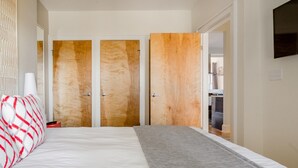 Un dormitorio con una cama, una mesita de noche y un armario de tres puertas.
