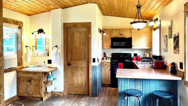 Una cocina con armarios de madera, una isla central con taburetes, un microondas y una estufa.