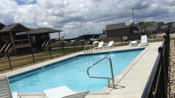 A swimming pool with lounge chairs and a fence.