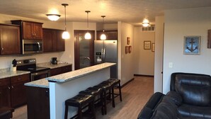 A modern kitchen with dark wood cabinets, stainless steel appliances, and a central island with bar stools.
