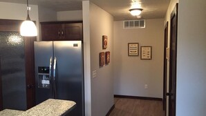 A kitchen with a refrigerator, a countertop, and a ceiling light fixture.