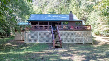 Situated in a wooded area, this cabin features a front porch and a white lattice fence for added seclusion.