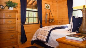 A wooden cabin bedroom with a bed, dresser, and a window with curtains. - Wonderful cabin on Fightingtown Creek, sleeps 8 (Epworth)