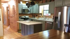 A kitchen with a central island, a microwave, a stove, and a refrigerator. - Wonderful cabin on Fightingtown Creek, sleeps 8 (Epworth)