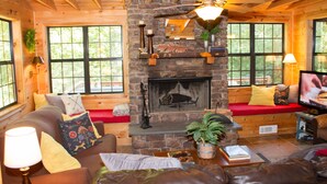 A cozy cabin interior with a stone fireplace, wooden beams, a leather sofa, and a television. - Wonderful cabin on Fightingtown Creek, sleeps 8 (Epworth)