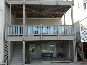 Un edificio de dos pisos con un balcón, una escalera y asientos exteriores.