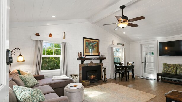 A spacious living room with a fireplace, a ceiling fan, and a television. - Private Cottage! Easy Walk Through The Park To Encinitas And Moonlight Beach. (Encinitas)