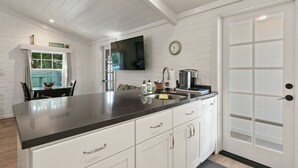 A modern kitchen with white cabinetry, a black countertop, a built-in oven, and a large window. - Private Cottage! Easy Walk Through The Park To Encinitas And Moonlight Beach. (Encinitas)