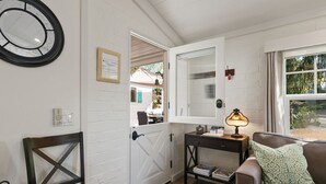 A cozy room with a white door, a mirror, a lamp, a sofa, and a small rug. - Private Cottage! Easy Walk Through The Park To Encinitas And Moonlight Beach. (Encinitas)
