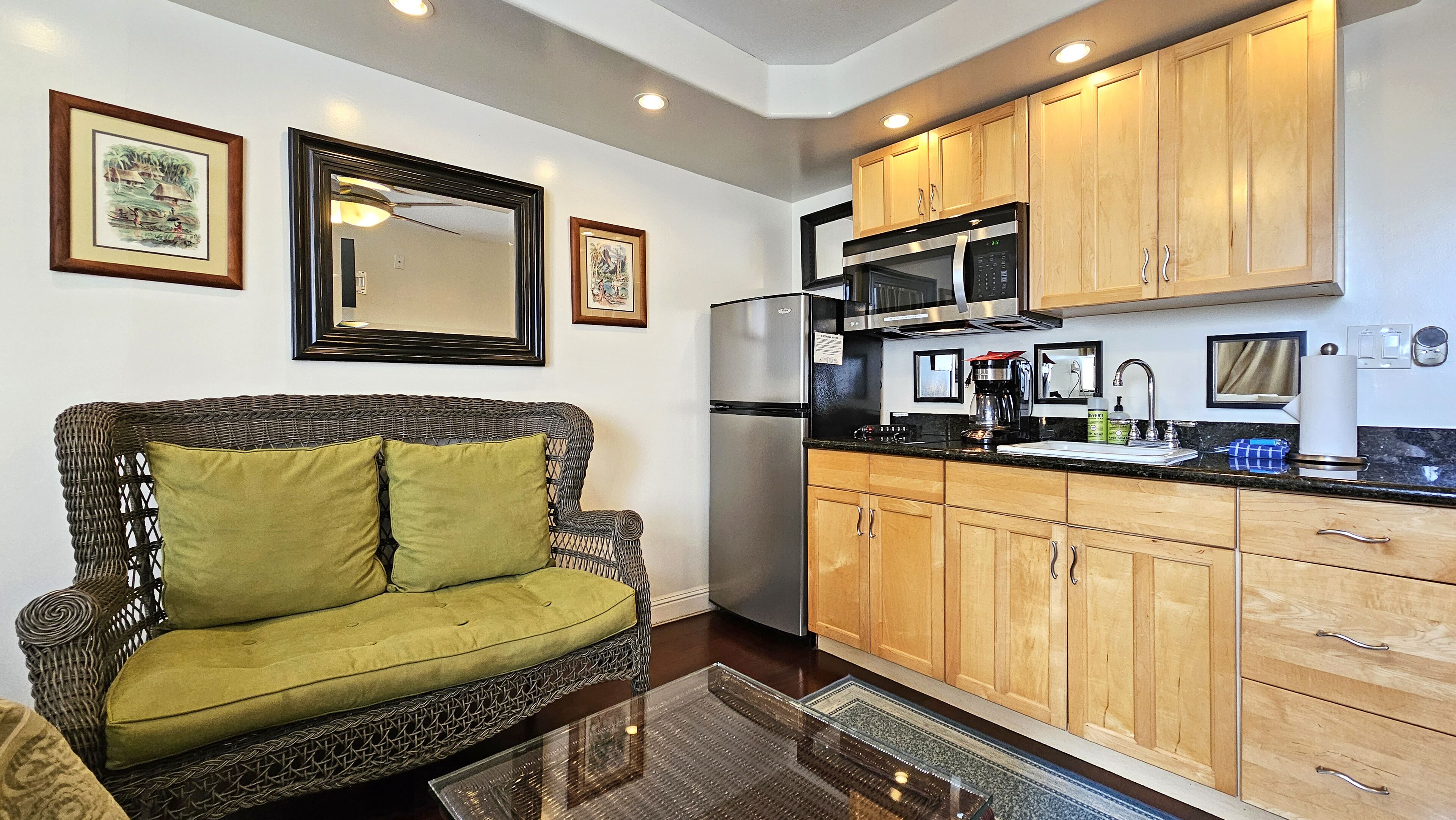 A compact living space with a sofa, kitchenette, and wooden cabinets.