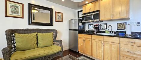 Un espacio habitable pequeño con sofá, kitchenette y armarios de madera.