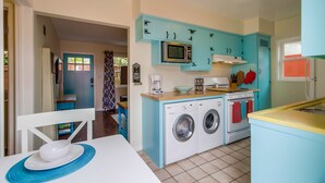 A compact kitchen with a washing machine, a microwave, and a stove.