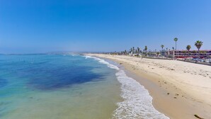 A beach with clear blue water, sandy shore, and palm trees.
