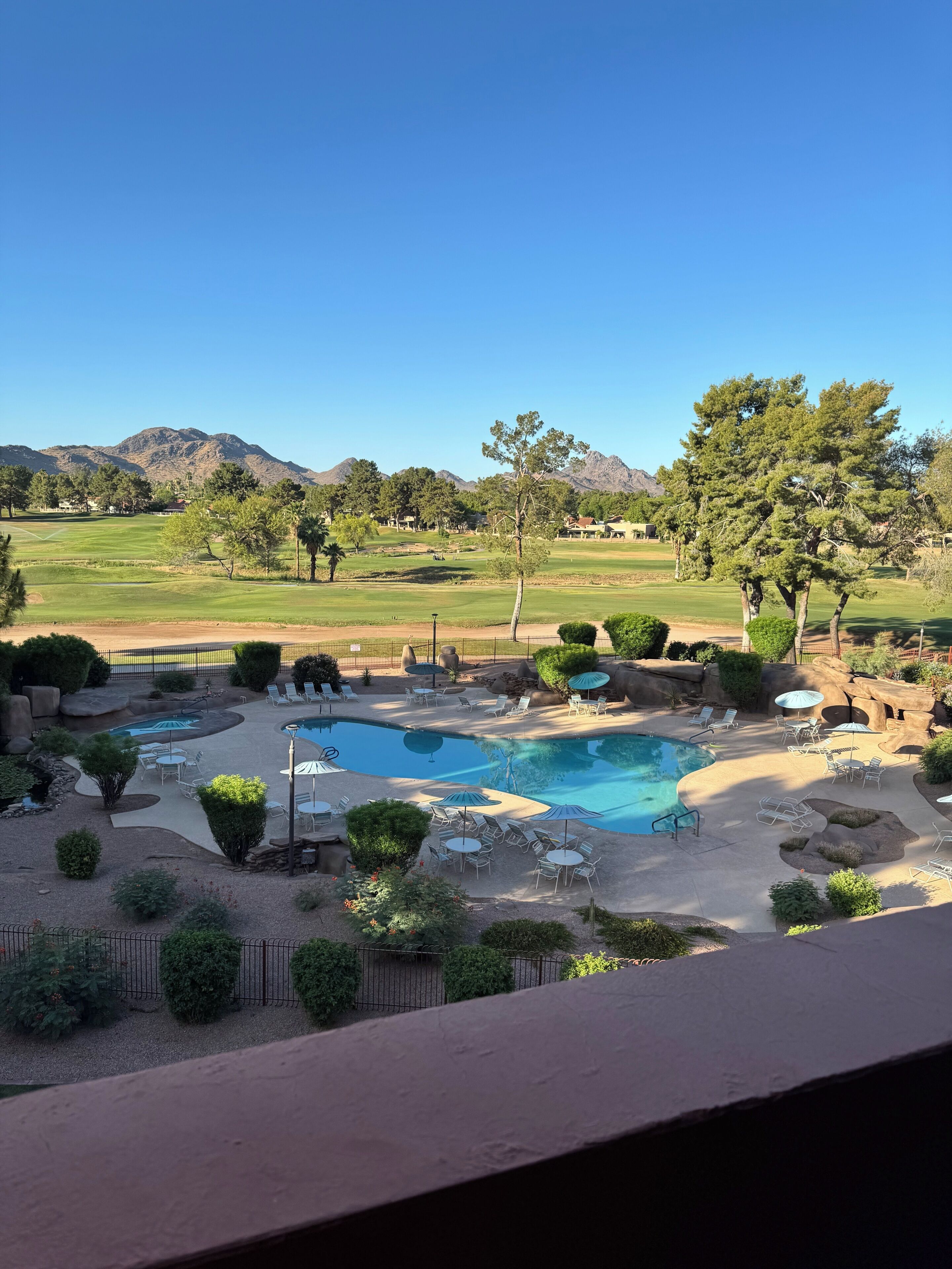 A pool area with multiple pools, lounge chairs, and a view of mountains.