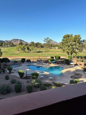 A pool area with multiple pools, lounge chairs, and a view of mountains.