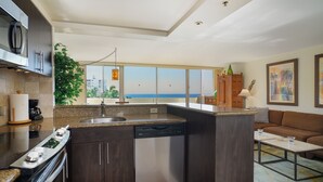 Een moderne keuken met een vaatwasser, een koffieapparaat en een groot raam met uitzicht op zee.