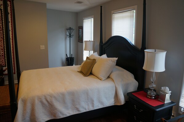 A neatly made bed with a black headboard, two bedside lamps, and a red tray on the nightstand.
