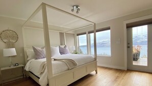 Una cama con dosel y vistas a un lago a través de amplias ventanas.