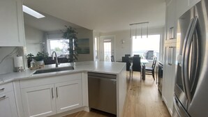 Una cocina moderna con armarios blancos, un refrigerador de acero inoxidable y una zona de comedor de madera.