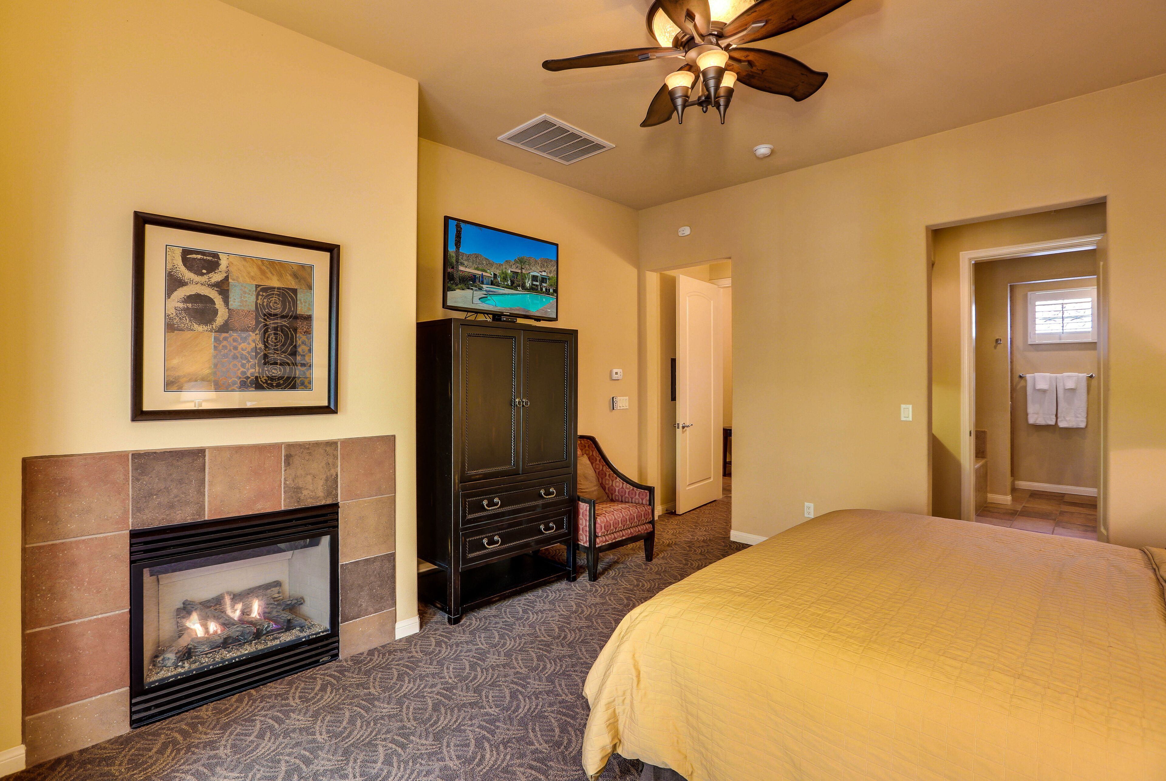 Habitación de hotel con chimenea, ventilador de techo, televisión y cama.