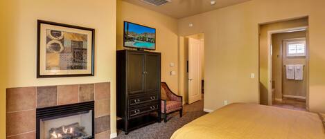Habitación de hotel con chimenea, ventilador de techo, televisión y cama.
