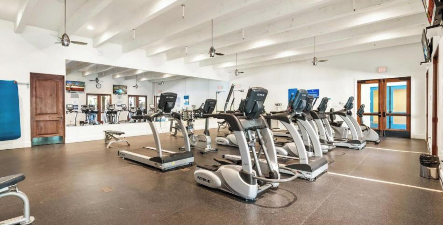 A gym with multiple treadmills arranged in rows.