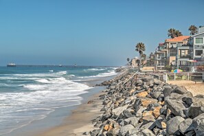 A coastal hotel with a rocky shoreline, a pier extending into the ocean, and a view of the sea.