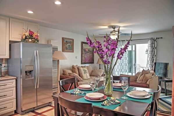 A modern kitchen with a stainless steel refrigerator, dining table set with plates, glasses, and a vase of flowers.