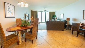 A spacious living area with a dining table, wicker chairs, a sofa, and a TV. - Rates just lowered.  Enjoy The WHITE BEACHES, LAZY RIVER, the CARIBE has it ALL (Orange Beach)