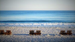 A beach with several wooden benches aligned parallel to the shore. - Rates just lowered.  Enjoy The WHITE BEACHES, LAZY RIVER, the CARIBE has it ALL (Orange Beach)