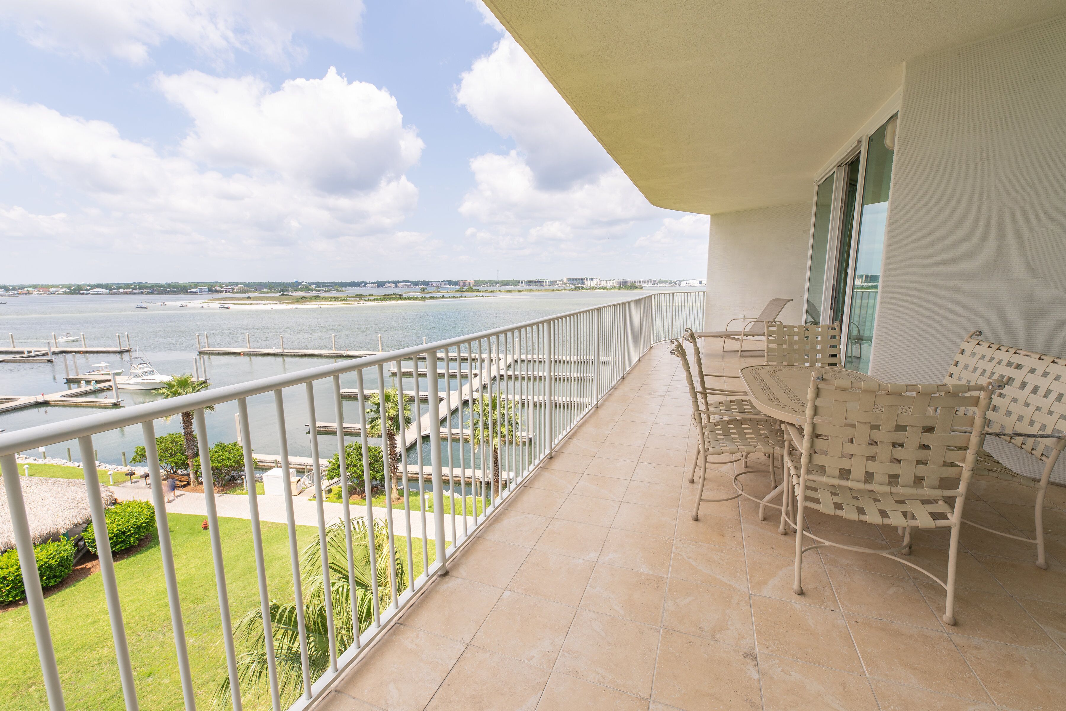 Een balkon met uitzicht op de jachthaven en het water. Er staan stoelen en een tafel op het balkon.