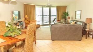 A living room with a sofa, chairs, a dining table, and a balcony with a view. - Rates just lowered.  Enjoy The WHITE BEACHES, LAZY RIVER, the CARIBE has it ALL (Orange Beach)