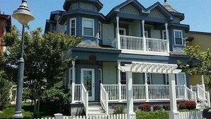 A two-story house with a balcony, a porch, and a small garden area. - Best Location In LBI! Walk To Everything (Beach Haven)