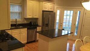 A kitchen with white cabinets, a stainless steel refrigerator, a dishwasher, and a black countertop. - Best Location In LBI! Walk To Everything (Beach Haven)