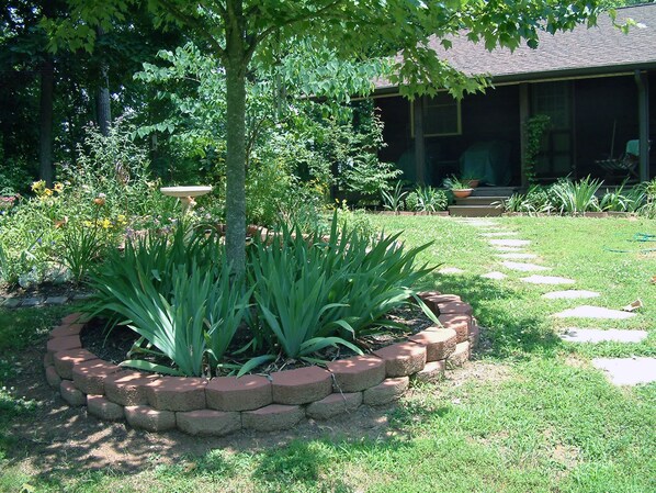A garden with a stone border, a tree, and a house in the background. - Top O' The Knob, Private Entrance, Romantic Getaway, Private Deck, and Fire Pit (Asheville)
