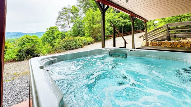 Ein Whirlpool unter einer Holzpergola mit Blick auf einen Wald und Berge.