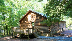 A log cabin with a wooden deck and a staircase leading to the entrance.