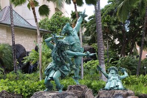 Estátua de uma mulher com uma criança em um jardim tropical.
