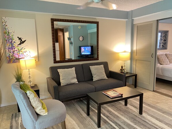 Ein Wohnzimmer mit einer Couch, einem Sessel, einem Couchtisch und einem Fernseher.