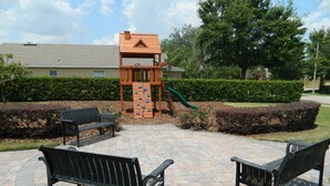 A playground with a climbing wall and slide, surrounded by benches and hedges. - Private Villa For Holiday Rental (Clermont)