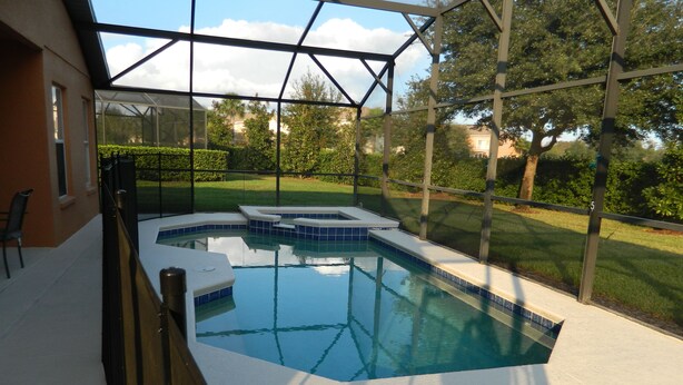 A swimming pool with a glass enclosure, surrounded by a well-maintained lawn and trees. - Private Villa For Holiday Rental (Clermont)